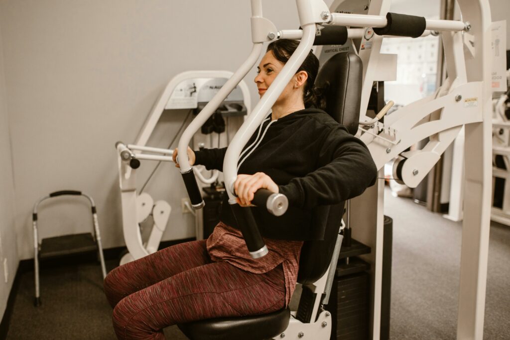 Woman working out on a chest press machine, promoting fitness and health in a gym setting.